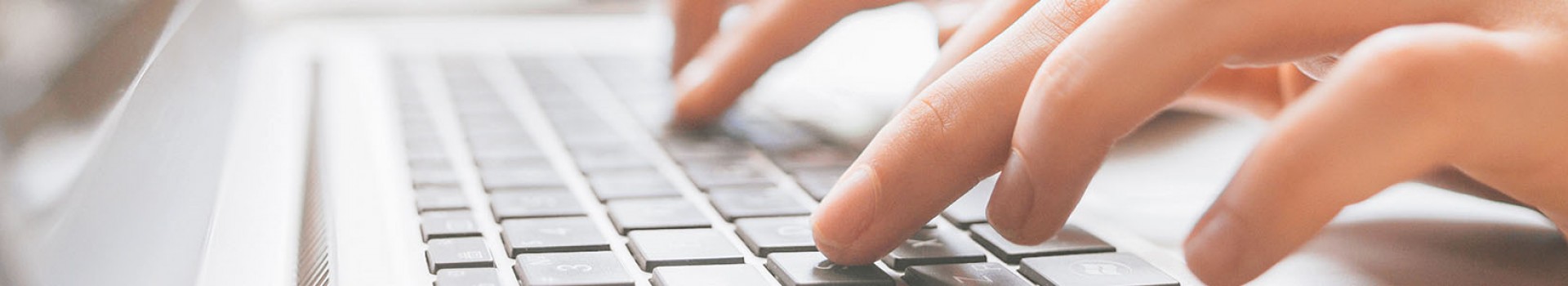 Hands typing on a laptop keyboard.