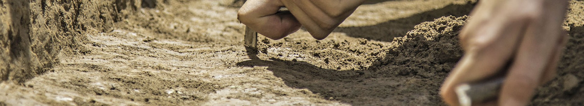 Trowelling hands in a trench.