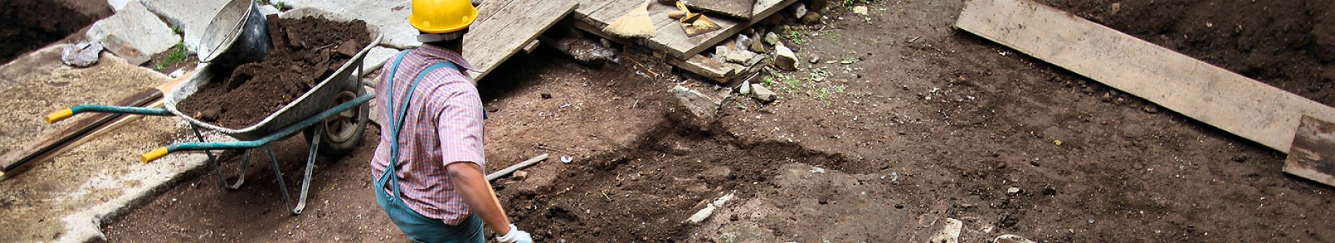 An archaeologist digs next to a barrow.