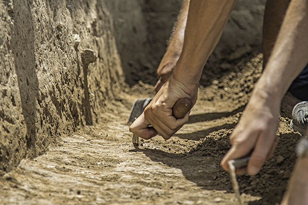 Trowelling hands in a trench.