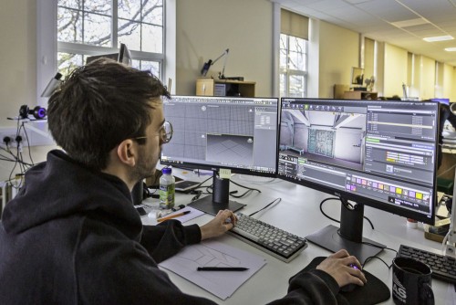 An archaeologist works on a 3D model of a building at a computer workstation.