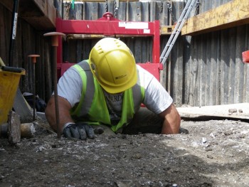 An archaeologist stands in a feature under excavation.